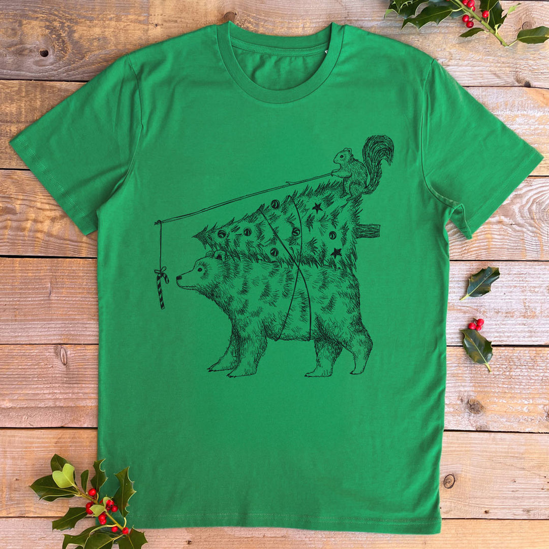 Green t-shirt with a bear and squirrel design on a wooden surface with holly leaves.