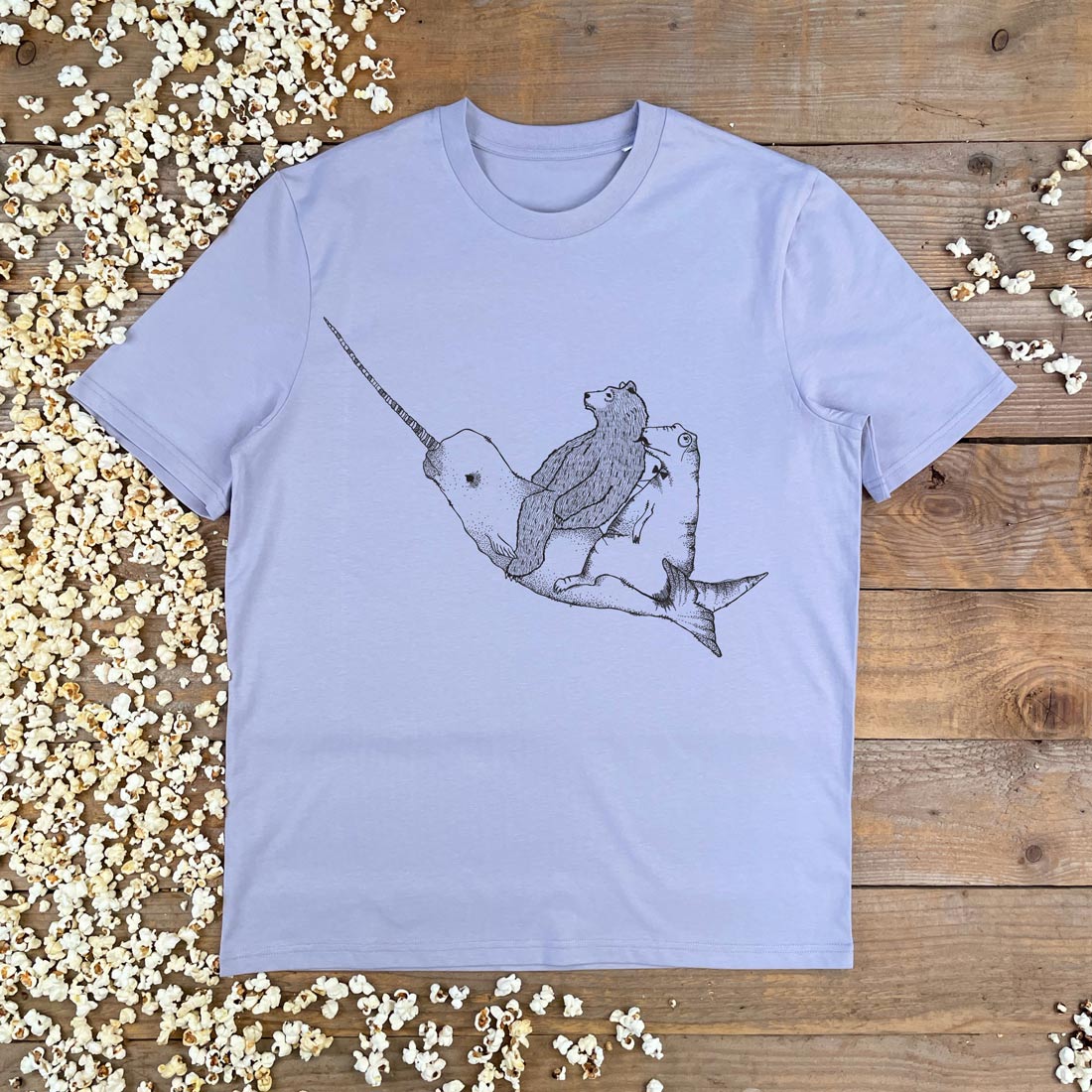 bear and dino riding a narwhal lilac tee